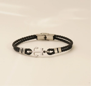 Détail d'un bracelet en cuir tressé noir avec une ancre argentée et un fermoir métallique chic