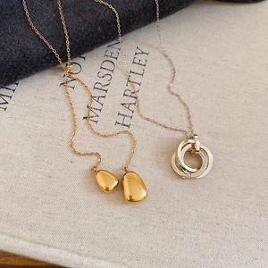 Detail of 18k gold plated teardrop and silver trinity rings on textured canvas