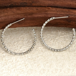 Close-up of silver 304 stainless steel hoop earrings with textured diamond pattern