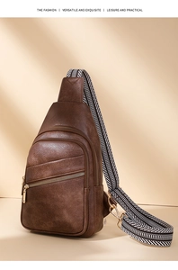 Detail showing brown leather sling bag texture and striped woven strap in warm lighting