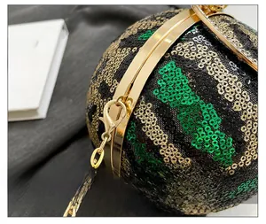 Macro detail of wave-patterned sequins and gold hardware on a spherical evening clutch