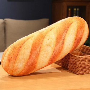 Realistisches Baguette-Brot Plüschkissen auf einem Holztisch mit Korb präsentiert.