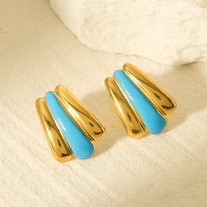 Close-up of golden fan-shaped earrings with blue enamel texture on light stone surface