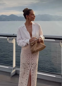 Vue détaillée de la jupe en maille ajourée beige avec chemise blanche sur un yacht