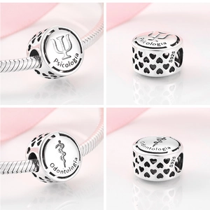 Close-up of S925 silver hollow charms for Psychology and Dentistry on a white surface