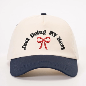 Cream and navy baseball cap with red bow embroidery and JUST DOING MY BEST slogan