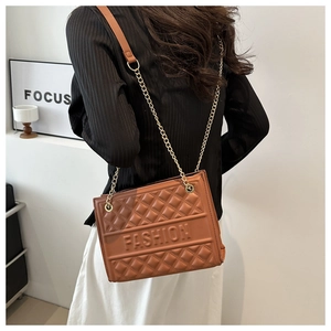 Detail of a brown quilted crossbody bag featuring a gold chain and embossed fashion text