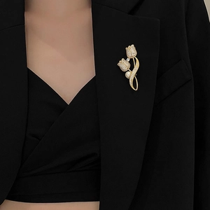 Elegant gold tulip brooch with sparkling rhinestones and a white pearl on a black suit
