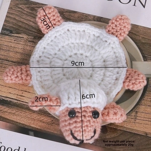 Detailed size view of handmade crochet sheep coaster featuring pink and white wool knit