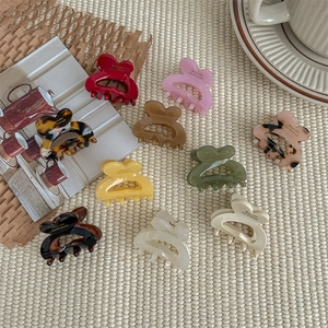 Multiple colorful heart-shaped acrylic claw clips on a neutral textured background
