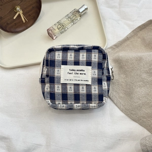 Detail view of square navy checkered storage pouch with fabric label on natural wood surface