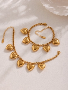 Nahaufnahme von goldfarbenem Gliederarmband aus Edelstahl mit polierten Herzanhängern