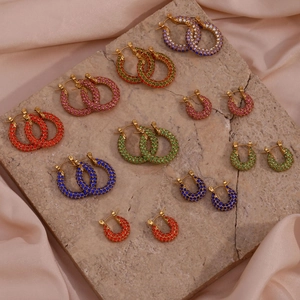 Close-up of diverse multi-colored zircon hoop earrings on elegant silk and stone textures