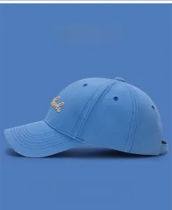 Detail of light blue cotton baseball cap featuring beige letter embroidery and metal buckle
