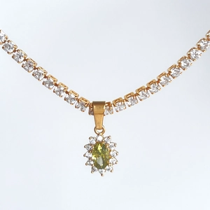 Macro detail of retro 18k gold plated necklace with oval green stone and zircon