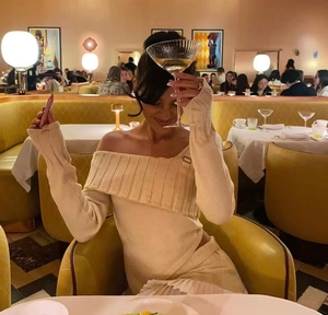 Detail of beige knit off-shoulder dress with layered collar design in a restaurant setting