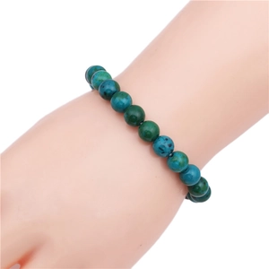 Detail of 8mm blue and green lapis bead bracelet worn on wrist over white background