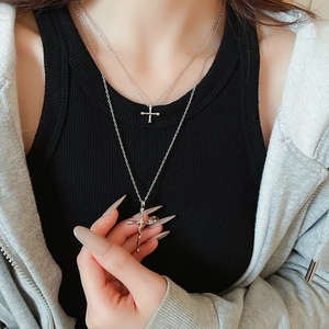 Macro view of layered silver cross necklaces with a liquid lava style pendant on a model