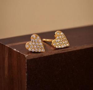 Macro view of gold heart stud earrings with micro-set shimmering cubic zirconia