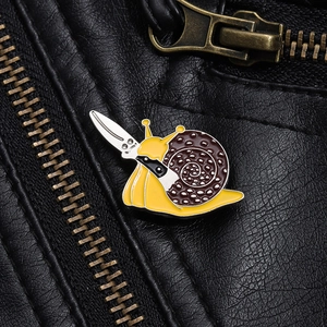 Macro view of cartoon snail enamel pin with a knife on a black leather jacket lapel