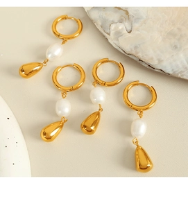 Dettaglio di eleganti orecchini con perla dorata e pendente a goccia su fondo beige
