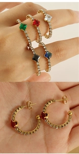 Gros plan de boucles d'oreilles créoles dorées serties de pierres multicolores
