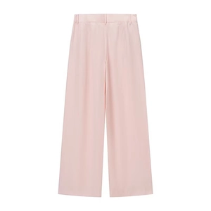 Detail of high-waisted pink wide-leg trousers with smooth drape and satin finish texture