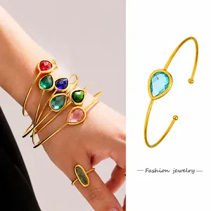 Dettaglio del bracciale aperto dorato e dell'anello con gemme colorate a goccia