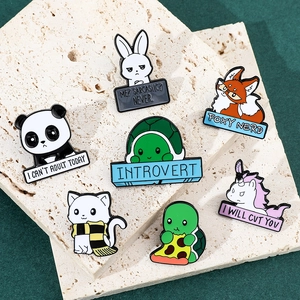 Close-up of enamel pins featuring cute animals with funny slogans on stone props