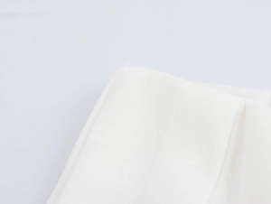 Dettaglio della trama del tessuto bianco e delle cuciture dei pantaloni a due pezzi