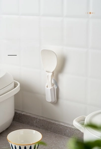 Detail view of suction cup rice spoon holder mounted on a clean white tile wall
