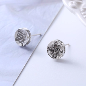 Macro view of round silver earrings with micro-set zircons and cross pattern