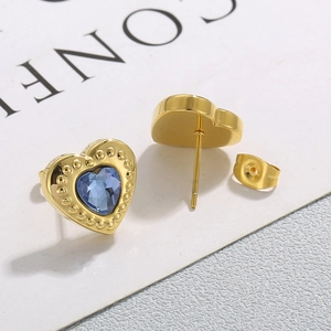 Goldene Herzohrstecker mit blauem Kristallstein für Damen vor schlichtem Hintergrund