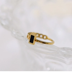 Detail of 18K gold-plated ring with black rectangular inlay and hollow chain design