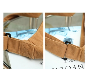 Detailed shot of brown canvas bag strap with black plastic buckle and reinforced stitching