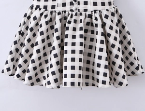 Detailed view of black and white plaid pleated skirt hem with woven fabric texture