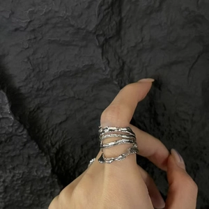 Detail of silver liquid metal layered ring with irregular lava texture on finger