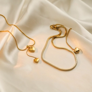 Minimalistische 18K vergoldete Herz-Halskette mit quadratischer Kette auf Seidenhintergrund