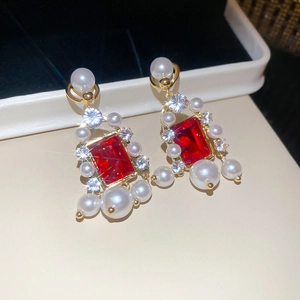 Vue macro de boucles d'oreilles vintage en or avec gemmes rouges et perles de luxe