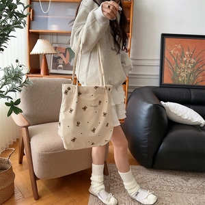 Detailed view of cream corduroy tote bag featuring cute bear embroidery on shoulder