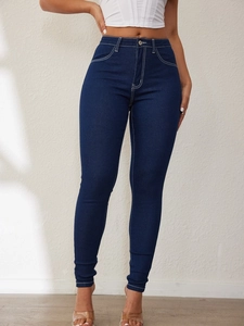Detailed close-up of dark blue high waist skinny jeans with white contrast stitching