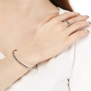 Polished silver stainless steel bangle and matching ring set worn on a female wrist
