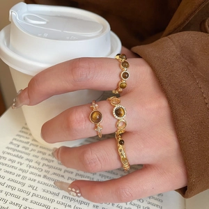 Macro view of four gold-plated rings with tiger eye stone on a model's hand