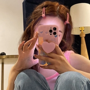 Pink heart-themed phone case with matching grip stand shown in a lifestyle mirror selfie