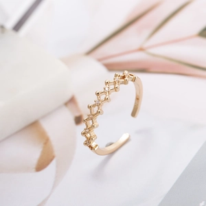 Elegant gold-tone open copper ring with zircon geometric mesh design on a natural stone base