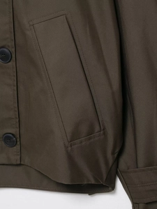 Detail of dark olive waterproof trench coat showing stitching and buttoned side pocket