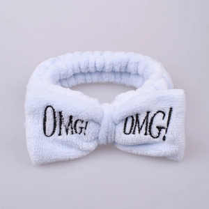 Macro detail of soft light blue plush headband featuring black OMG! embroidered bow