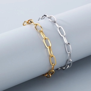 Close-up of gold and silver stainless steel rectangle link chains on a grey display