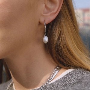 Elegant stainless steel C-hoop earrings with freshwater pearl drops on female model