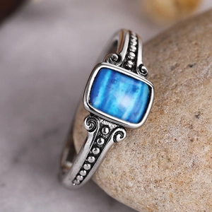 Detail of vintage silver ring with blue square stone on pebble stone background